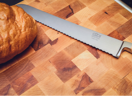 serrated knife and loaf of bread on butcher block