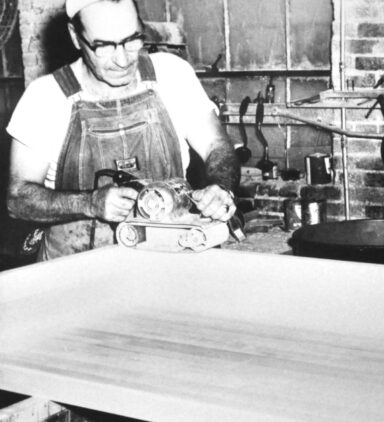 historical photo of woodworker sanding butcher block