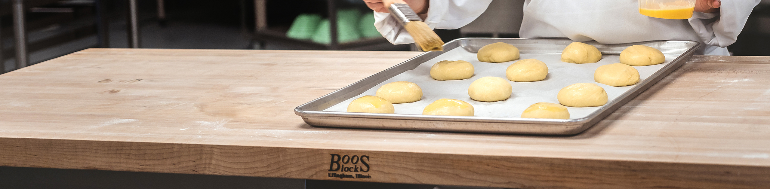 baker egg washing dough on top of butcher block countertop